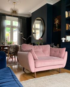 an instagram photo of a living room with blue walls and pink couches in it