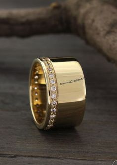 a gold ring with white diamonds on it sitting on a wooden table next to a branch