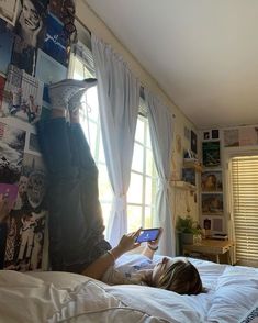 a person laying on a bed with a book in their hand and looking at the screen