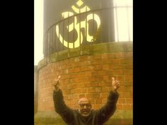 a man standing in front of a brick building with his hands up and the number 55 on it