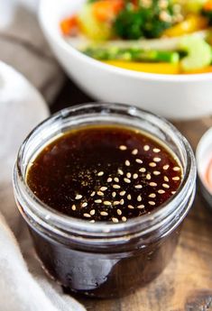 a bowl of vegetables next to a jar of sauce