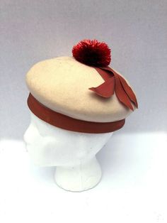 Adorable Rare Mr.John New York/ Paris Juniorette felt pom pom hat. Mr John's most famous work was his millinery for Vivien Leigh in Gone With The Wind. he had a long association with Hollywood and Broadway. He attributed all his success to Mary Pickford. Hat is ivory felt with rusty red colored raffia pom pom and apricot colored grosgrain ribbon. Some light spots on grosgrain ribbon as shown. Sold as-is.  This is a final sale. measurements inside circumference 19.5 FAQ:Terms and Info regarding i Vintage Red Hat For Fall, Vintage Beige Felt Hat For Winter, Vintage Wool Beret For Winter, Vintage Winter Beret With Short Brim, Retro Winter Beret, Madeline Aesthetic, Pom Pom Clothes, Felt Pom Pom, Fashion 1950