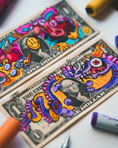 two dollar bills with cartoon characters on them and crayon markers next to them