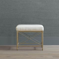 a white bench sitting on top of a hard wood floor next to a gray wall