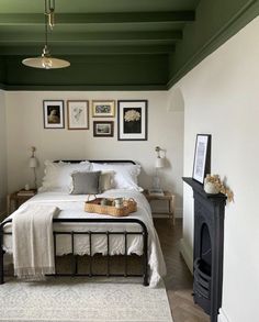 a bedroom with green painted ceiling, white bedding and pictures on the wall above it