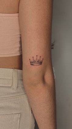 a woman's arm with a small crown tattoo on the left side of her arm