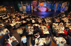 an overhead view of people eating at tables in a large room with stage and lights