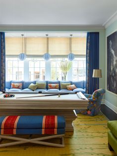 a living room with blue couches and colorful pillows on the floor, along with other furniture