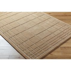 a beige area rug with squares and lines on the floor in front of a wooden floor