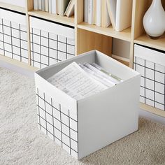 a white box with papers in it sitting on the floor next to bookshelves