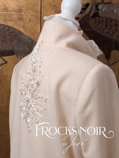 the back of a white coat with beading on it and an eagle in the background