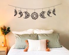 there is a bed with white sheets and pillows on the headboard, along with three decorative wall hangings