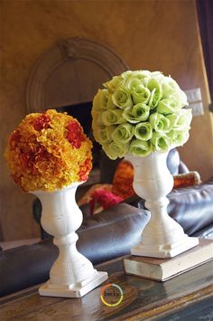 two white vases filled with flowers on top of a table