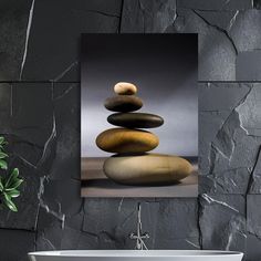 a white tub sitting next to a black wall with rocks on it and a green plant in the corner