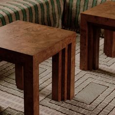 two wooden tables sitting on top of a carpeted floor next to a couch in a living room