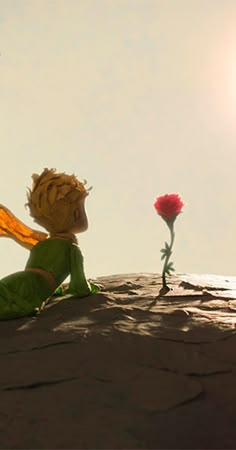 a toy tinkerbell sitting on top of a rock next to a red rose