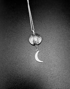 Embrace the celestial beauty with our handcrafted sterling silver pendant featuring a textured full moon cradling a delicate crescent moon. Each detail captures the mystique of the night sky, making this pendant a symbol of harmony and celestial wonder. Perfect for those drawn to lunar symbolism or seeking a meaningful gift, this piece combines craftsmanship with cosmic allure. Add a touch of celestial elegance to your collection with this unique pendant, designed to inspire and enchant. Silver Moon-shaped Jewelry With Coin Pendant, Sterling Silver Moon Necklace With Coin Pendant, Moon Shaped Sterling Silver Necklace With Coin Pendant, Silver Moon Necklace With Coin Pendant, Silver Moon Print Round Jewelry, Moon Texture, Celestial Jewelry, Unique Pendant, Crescent Moon