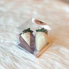 two chocolate covered strawberries in a clear box on a white furnishing surface