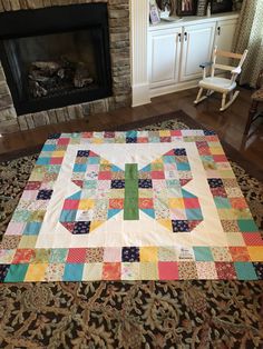 a living room with a fire place and a large quilt on the floor in front of a fireplace