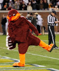 a mascot is kicking a football on the field