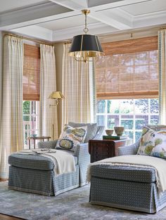 a living room with two couches and a chair in front of a window filled with curtains