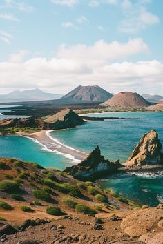 an island in the middle of some water with mountains in the backgrouds