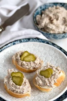 three small sandwiches with pickles on them are sitting on a plate next to a fork