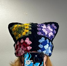 a woman taking a selfie with her cell phone wearing a crocheted cat hat