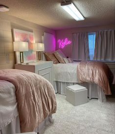 two beds in a room with pink lights on the wall and white rugs underneath them