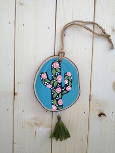 a wooden wall hanging with a cactus painted on it's side and tassel