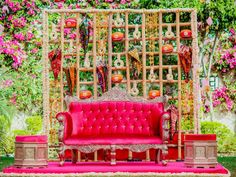 a red couch sitting on top of a pink carpet covered ground next to a wooden trellis