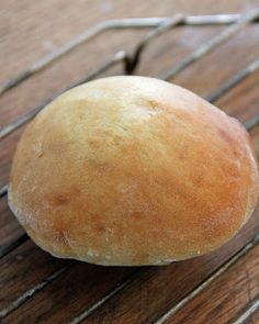 a round loaf of bread sitting on top of a wooden table next to a wire rack