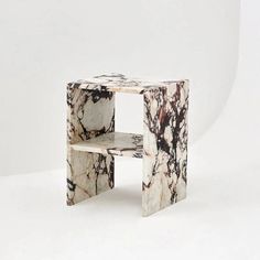 a white and black marbled side table with two shelves on each side, in front of a white background