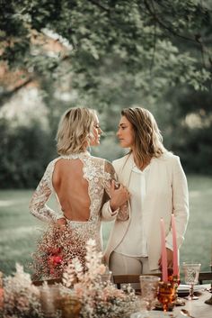 two women standing next to each other in front of a table with candles and flowers