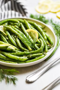 a white plate topped with green beans and lemon slices