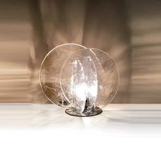 two clear glass plates sitting on top of a white table next to a brown wall