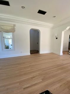 an empty living room with hard wood flooring and white paint on the walls,