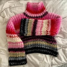 a knitted sweater laying on top of a bed