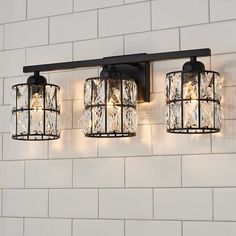 three lights that are on the side of a wall next to a white brick wall