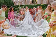 a group of women standing around each other in front of a wedding dress and veil