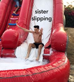 a man sitting on top of a giant inflatable water slide that says sister slipping