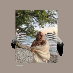 a woman wrapped in a towel standing next to the ocean with hands reaching out towards her