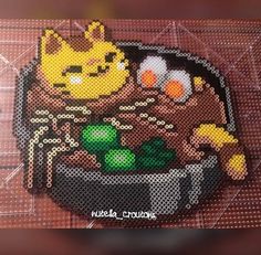 a cross - stitch picture of a bowl of food with an angry cat on it