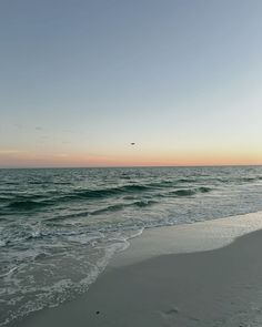 the sun is setting at the beach with waves coming in