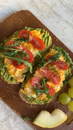 an open face sandwich with tomatoes, avocado and cheese on a cutting board