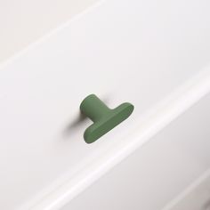 a green handle on a white cabinet door