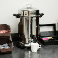 a coffee pot sitting on top of a counter next to a cup and other items