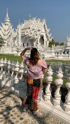 a woman is taking a photo in front of a white temple