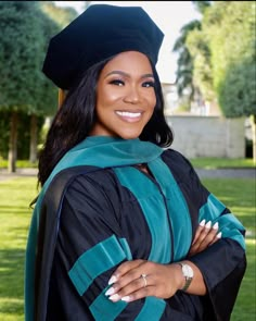 a woman in a graduation gown and cap posing for a photo with her arms crossed