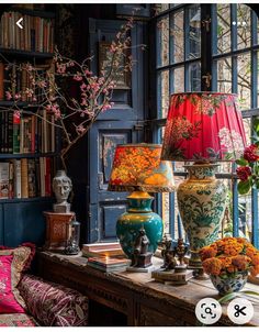 a table with vases and lamps on it in front of a bookcase filled with books